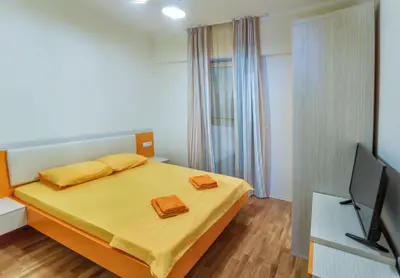 a bedroom with a bed with yellow sheets and a television at Sea View Apartments MonteBook in Becici