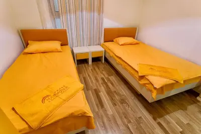 two beds in a small room with yellow sheets at Sea View Apartments MonteBook in Becici