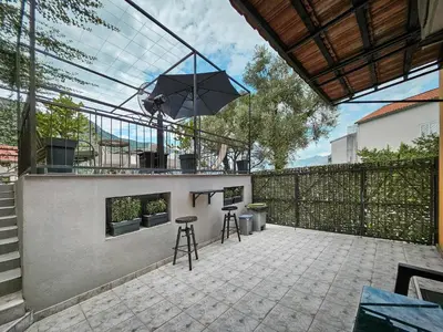 a patio with a table and chairs and an umbrella at Holiday House Kotor in Kotor