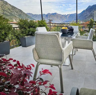 a patio with a table and chairs and mountains at Holiday House Kotor in Kotor