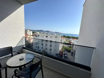 a balcony with a table and chairs and a large window at Apartmani Kojić 2 in Bar, Susanj