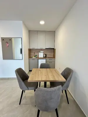 a dining room table with two chairs and a kitchen at Apartmani Kojić 2 in Bar, Susanj