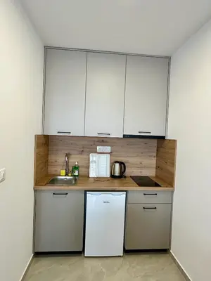 a small kitchen with white cabinets and a sink at Apartmani Kojić 2 in Bar, Susanj