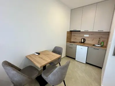 a small kitchen with a wooden table and chairs at Apartmani Kojić 2 in Bar, Susanj