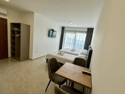 a room with a table and a bed and a window at Apartmani Kojić 2 in Bar, Susanj