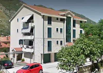 a red car parked in front of a white building at Megy Apartment with parking and sea view in Kotor