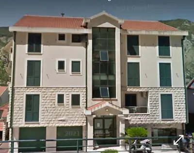 a large apartment building with a sign on it at Megy Apartment with parking and sea view in Kotor
