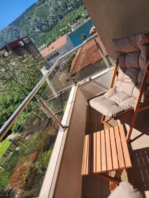 a balcony with a chair and a glass railing at Megy Apartment with parking and sea view in Kotor