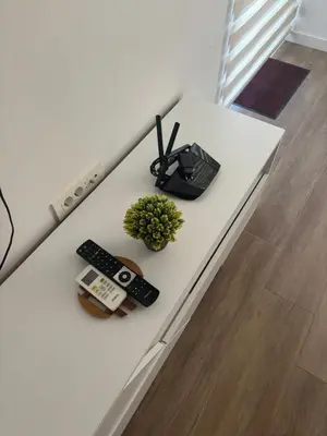 a white table with remote controls and a plant on it at Mira Apartment in Dobra Voda
