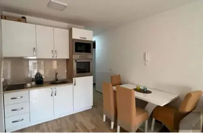 a kitchen with white cabinets and a table and chairs at Hana Apartments in Dobra Voda