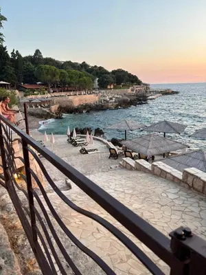 a beach with umbrellas and people in the water at Hana Apartments in Dobra Voda