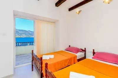 two beds in a room with a view of the ocean at Apartments Bella di Boka in Tivat