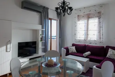 a living room with a purple couch and a glass table at Apartment Taurus in Petrovac na Moru