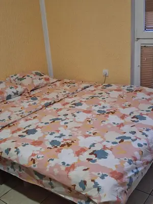 a bed with a flowery comforter on it at Apartments D&D Sutomore in Sutomore