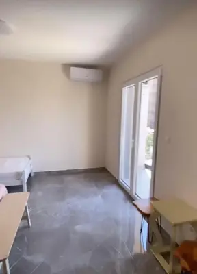 a room with a large window and a room with a table at Fenix Apartmani Dubrava in Dobra Voda