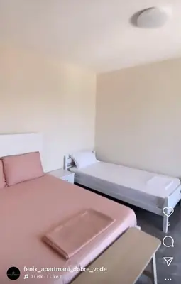 a small room with two beds and a table at Fenix Apartmani Dubrava in Dobra Voda