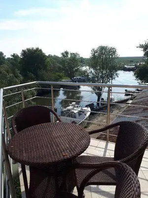 two chairs and a table on a balcony with a boat in the water at Apartment Biba in Virpazar