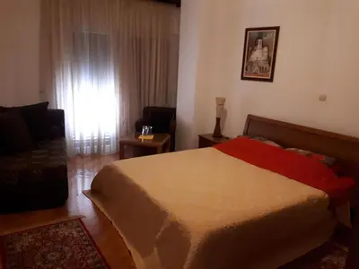 a bedroom with a bed and a couch and a window at Apartment Biba in Virpazar