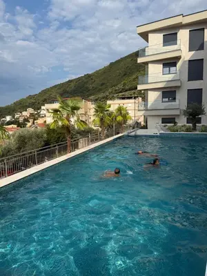 two people swimming in a swimming pool next to a building at Nicks sea view appartement II in Petrovac na Moru