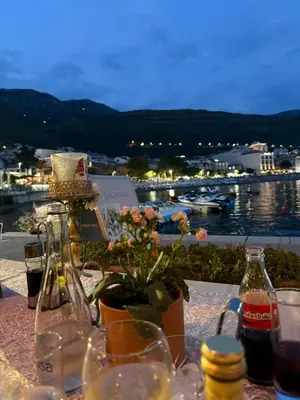 a table with wine bottles and a view of a harbor at Nicks sea view appartement II in Petrovac na Moru