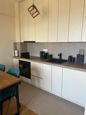 a kitchen with white cabinets and a wooden table at Nicks sea view appartement II in Petrovac na Moru