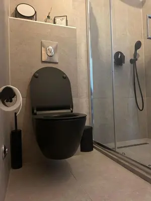 a bathroom with a black toilet and a shower at Nicks sea view appartement II in Petrovac na Moru