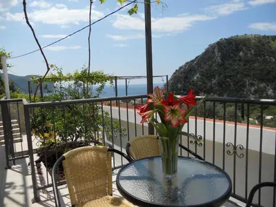 a glass table with a vase of flowers on a balcony at Apartment Djukovic in Petrovac na Moru