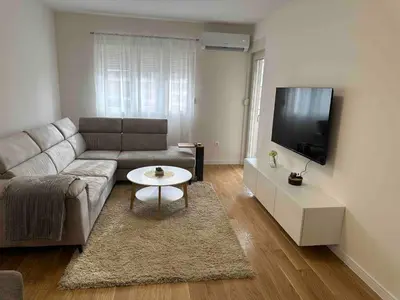 a living room with a couch and a flat screen tv at Stylish one bedroom apartment Central Point with -GARAGE 5 EUR PER DAY in Podgorica