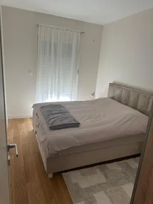 a bed in a white bedroom with a window at Stylish one bedroom apartment Central Point with -GARAGE 5 EUR PER DAY in Podgorica