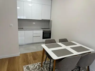 a kitchen with white cabinets and a table and chairs at Stylish one bedroom apartment Central Point with -GARAGE 5 EUR PER DAY in Podgorica