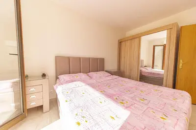 a bedroom with a bed with a pink comforter and a mirror at Apartment Sofija Petrovac in Petrovac na Moru