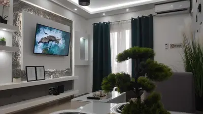a living room with blue curtains and a tv on the wall at AJKULICA Apartman in Bar
