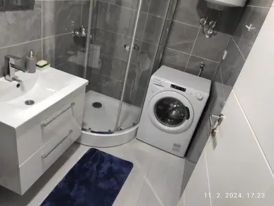 a bathroom with a washing machine and a sink at AJKULICA Apartman in Bar
