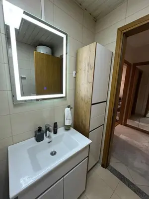 a bathroom with a sink and a mirror and a refrigerator at IN apartment in Podgorica