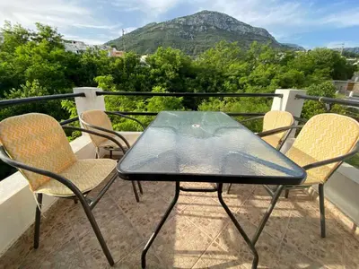 a table and chairs on a balcony with a mountain at Studios Zoran Milosev in Bar