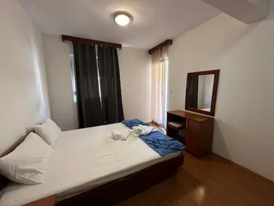 a small bedroom with a bed and a mirror at Apartmani Jovan in Budva