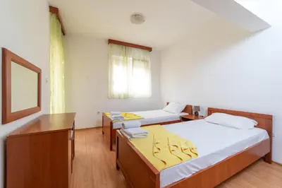 a room with two beds and a desk and a window at Apartmani Jovan in Budva