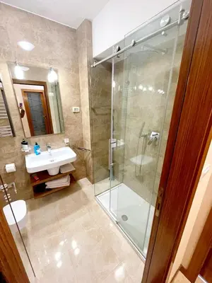 a bathroom with a glass shower and a sink at City center apartment in Podgorica