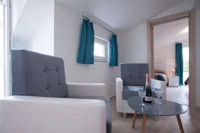 a living room with a couch and a table with a bottle of wine at Apartments Kuljace in Sveti Stefan