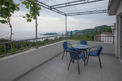 a balcony with chairs and a table and a view at Apartments Kuljace in Sveti Stefan
