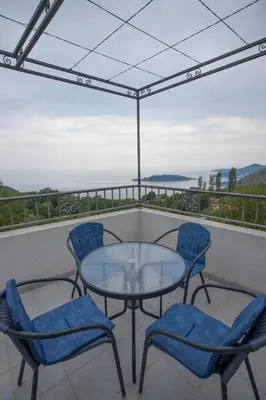 a glass table and chairs on a balcony with a view at Apartments Kuljace in Sveti Stefan