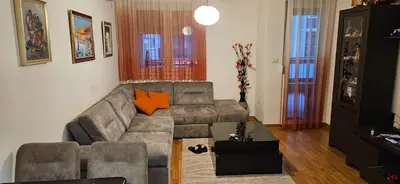 a living room with a gray couch and orange pillows at City kvart apartment in Podgorica