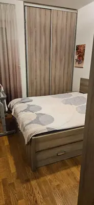 a bed with a wooden headboard in a room at City kvart apartment in Podgorica