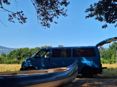 a blue van parked next to a boat in front at Camper t4 in Danilovgrad