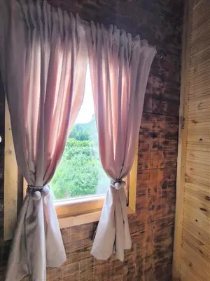 a window with pink curtains in a room at Wooden Lakeside Cottage in Virpazar