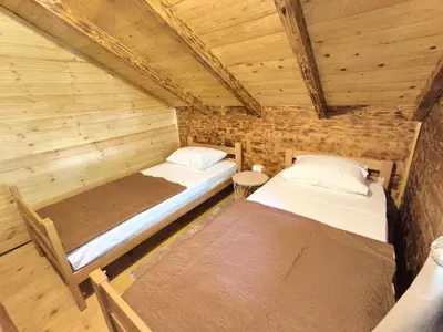 two beds in a room with wooden walls at Wooden Lakeside Cottage in Virpazar