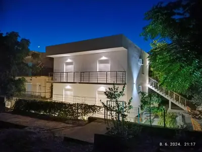 a white building with a balcony at night at More i Vuk in Bar