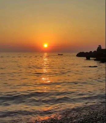 a sunset over the ocean with a boat in the water at More i Vuk in Bar