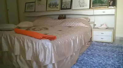 a bedroom with a bed with an orange blanket on it at Family House Pavicevic in Bar