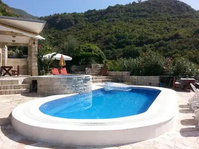 a large swimming pool in a patio with a mountain at Villa Royal Dream in Sveti Stefan